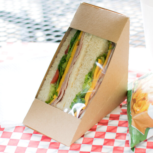 A sandwich in a Kraft paper sandwich wedge container with a window.