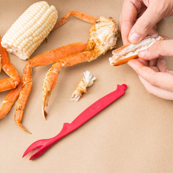 A person using a red WNA Comet Sea-Sheller to hold a crab claw.