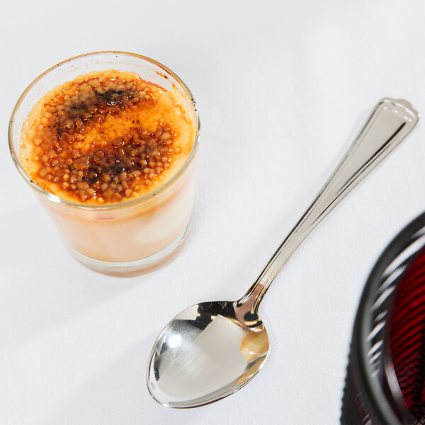 A Libbey stainless steel dessert spoon next to a glass of dessert.