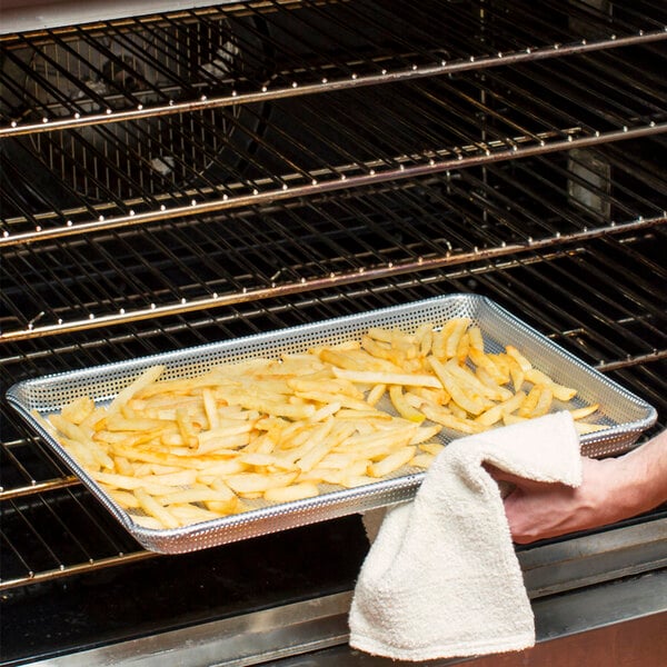 French fries in a Thunder Group fully perforated bun pan on a counter.