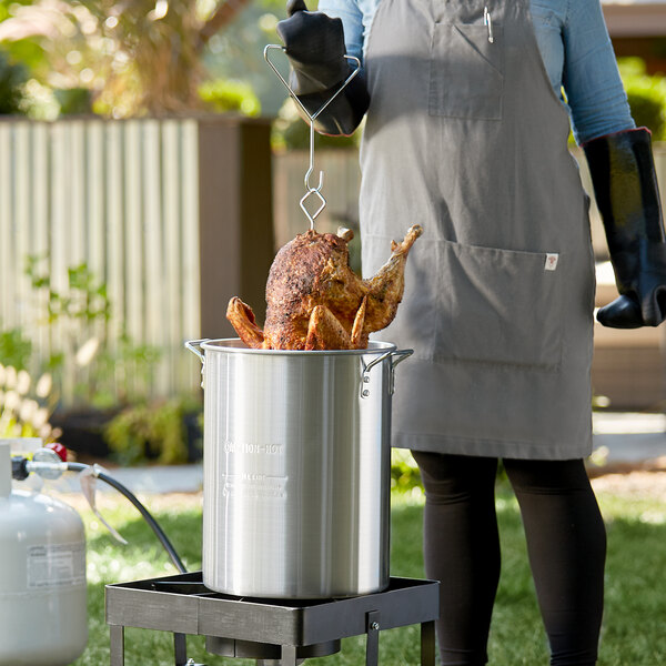 A woman using a Backyard Pro turkey fryer to cook a turkey.