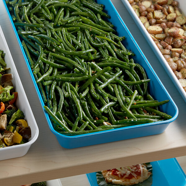 A blue Cambro fiberglass market pan on a counter filled with a tray of green beans and potatoes.