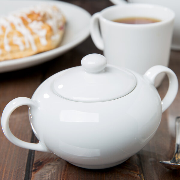 A white porcelain sugar bowl with a lid on a white background.