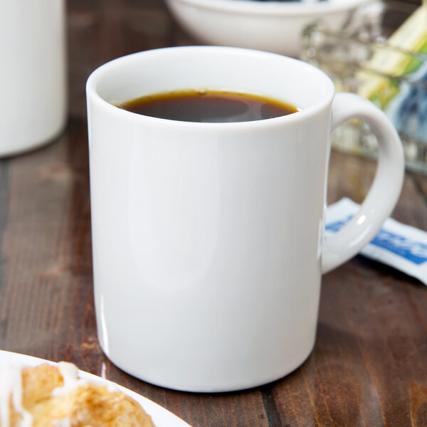 A white 10 Strawberry Street porcelain mug filled with coffee on a table.