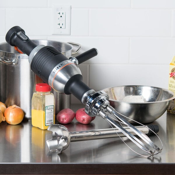 A KitchenAid immersion blender mixing ingredients on a counter.