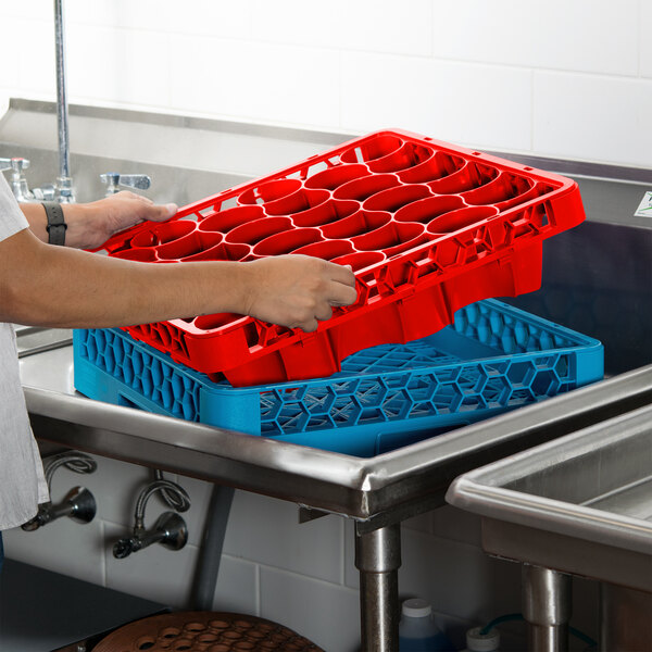 A person holding a red Carlisle glass rack extender over a sink.