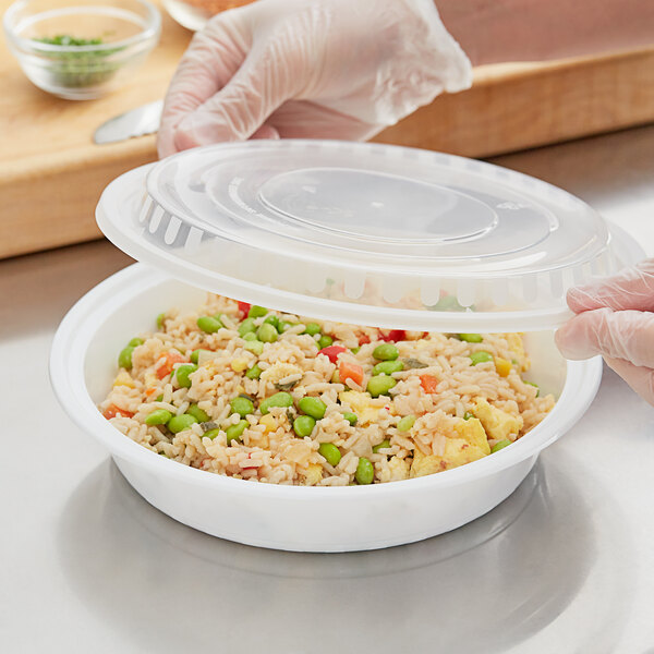 A person using a Choice white microwavable container lid to cover a bowl of food.