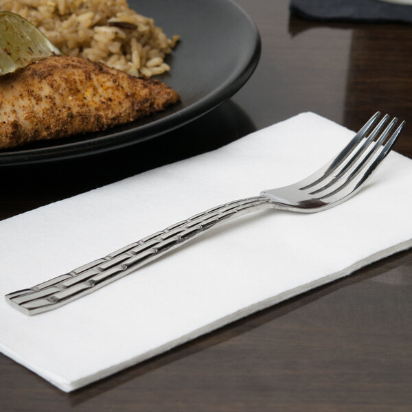 A 10 Strawberry Street Panther Link stainless steel salad fork on a napkin next to a plate of food.