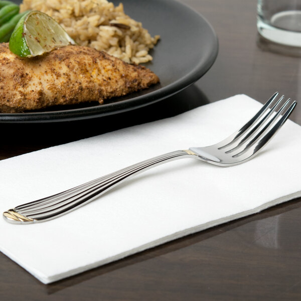 A 10 Strawberry Street Parisian gold stainless steel salad fork on a napkin next to a plate of food.