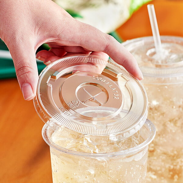 A hand holding a Choice clear plastic lid on a plastic cup with a straw.