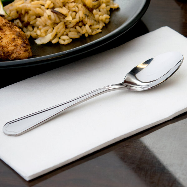 A 10 Strawberry Street Lincoln stainless steel teaspoon on a napkin next to a plate of food.