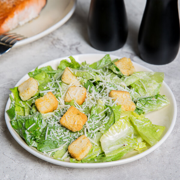 A plate of salad with croutons and cheese on a sand porcelain plate.