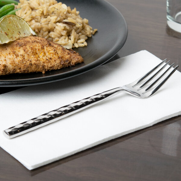 A 10 Strawberry Street stainless steel salad fork on a napkin next to a plate of food.