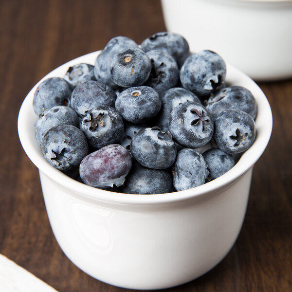 A white porcelain bowl filled with blueberries.