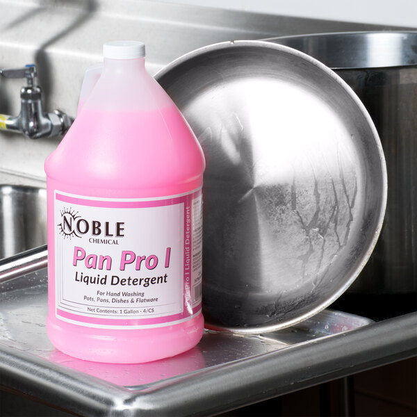 A silver bottle of Noble Chemical Pan Pro I liquid detergent on a counter in a professional kitchen.