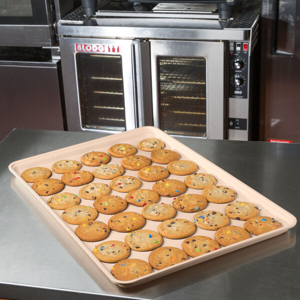 A MFG Tray 18" x 26" peach fiberglass market tray of cookies on a counter.
