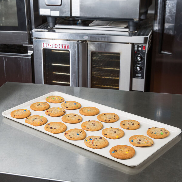 A MFG Tray eggshell fiberglass display tray holding cookies with candy on a counter.