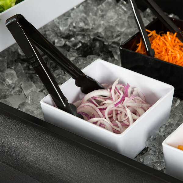 A Tablecraft white melamine bowl filled with chopped onions on a table in a salad bar.