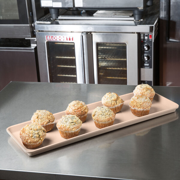 A MFG Tray supreme display tray of muffins on a counter in a bakery.