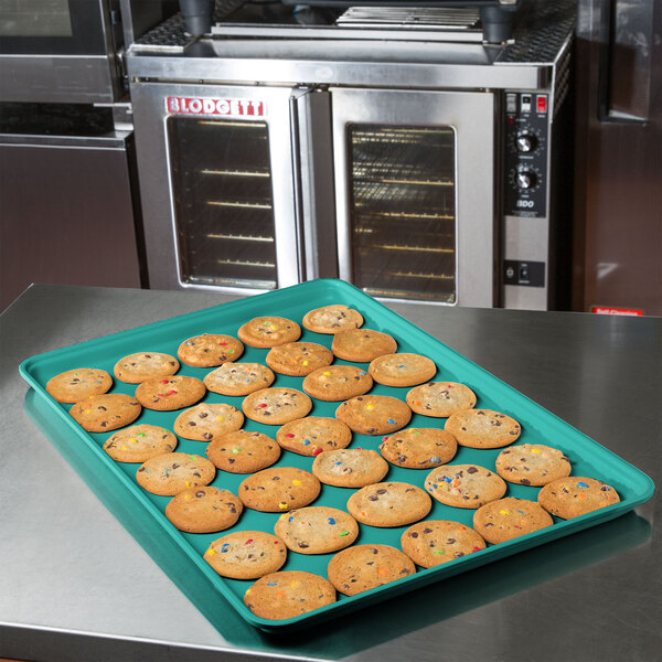 A MFG Tray mint green fiberglass display tray of cookies on a kitchen counter.