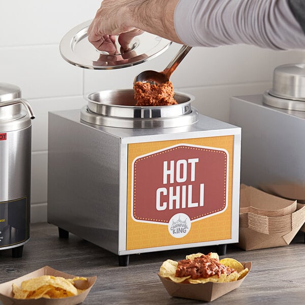 A person using a Carnival King condiment warmer to serve hot chili.