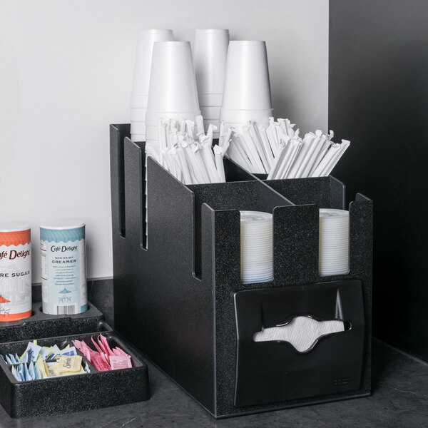 A black Vollrath countertop organizer with white cups and straws.