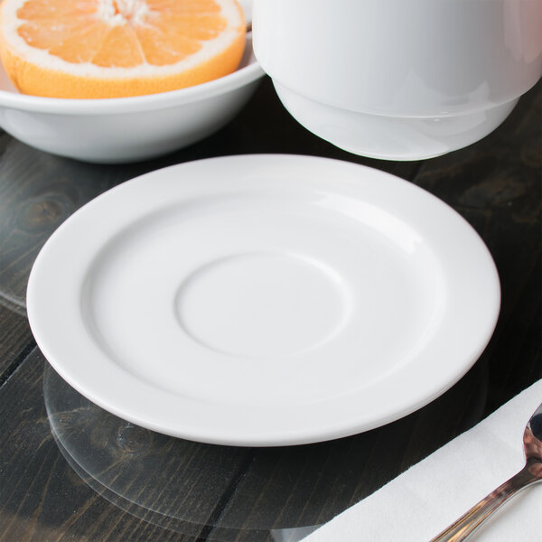 A Libbey white porcelain tea saucer with a bowl of orange slices and a spoon.