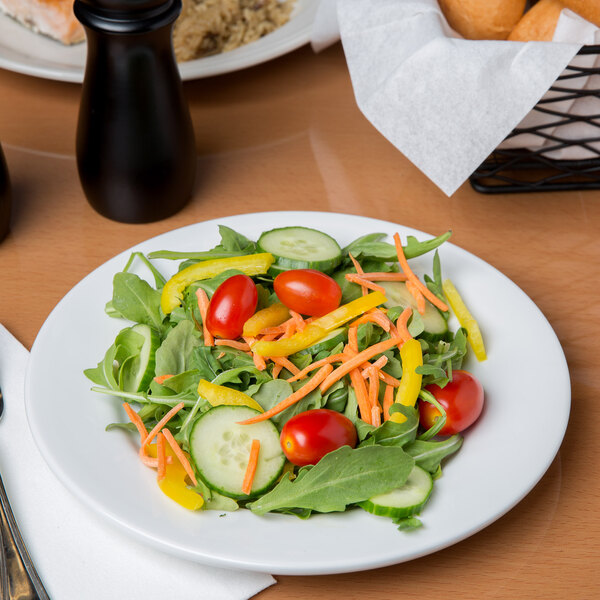 A Libbey aluma white porcelain plate with a vegetable salad on a table.