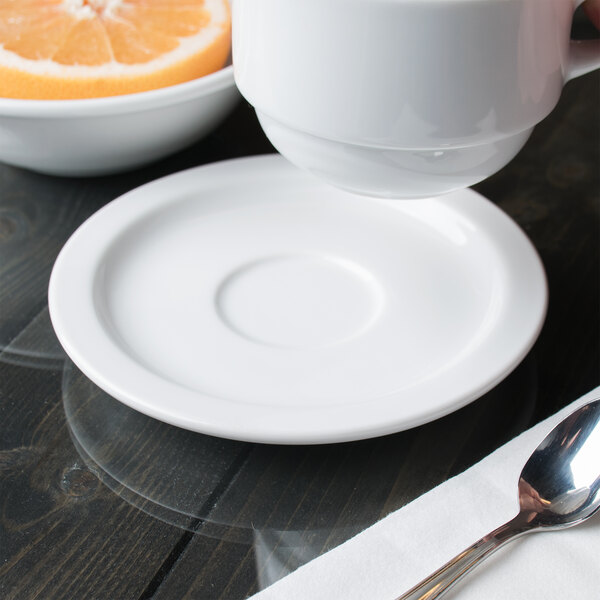 A Libbey Aluma White porcelain saucer holding a white tea cup on a saucer with a spoon.