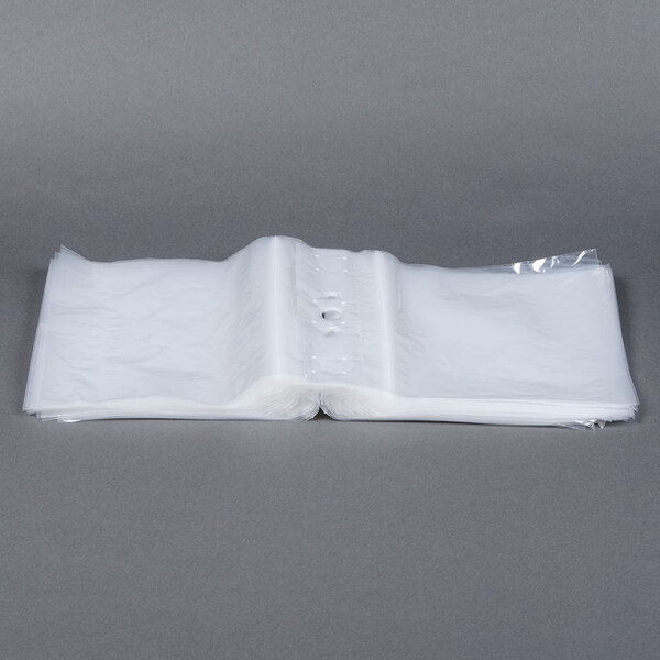 A stack of unprinted white plastic deli saddle bags with seal tops.