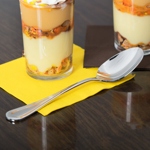 A Libbey stainless steel dessert spoon in a glass of dessert on a table.