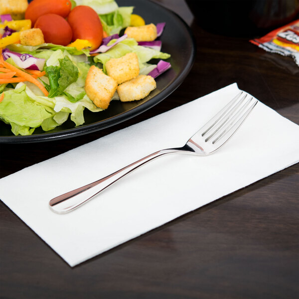 A Libbey stainless steel salad fork on a plate of salad with croutons and tomatoes.