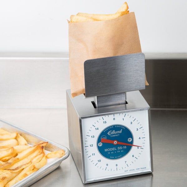 An Edlund mechanical portion scale with a box of french fries on it.