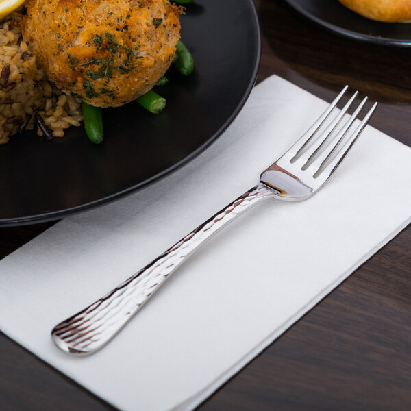 A Libbey stainless steel dinner fork on a plate of food.