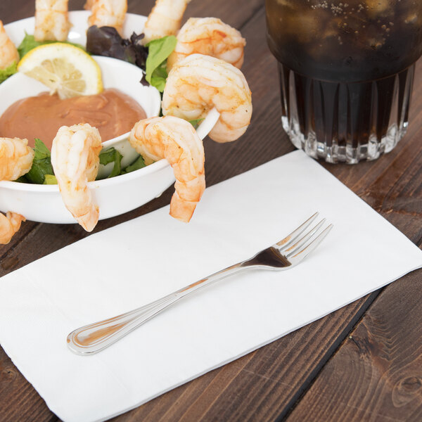 A bowl of shrimp with sauce and a Libbey cocktail fork on a napkin.