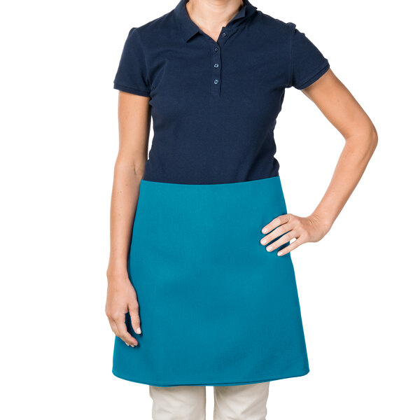 A woman wearing a teal Intedge waist apron over a blue shirt and white pants.