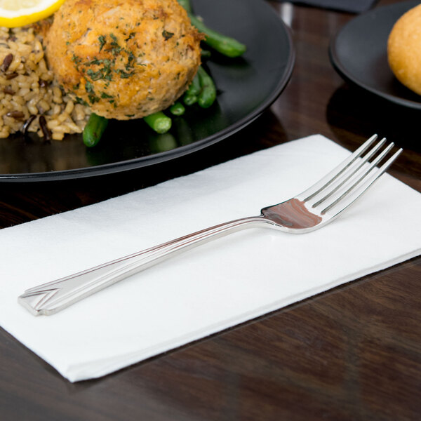 A World Tableware Varese stainless steel utility fork on a white napkin next to a plate of food.