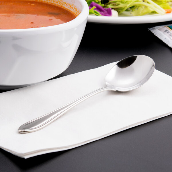 A bowl of soup and a spoon on a table.
