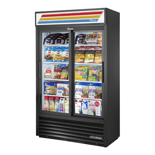 A black True convenience store merchandiser refrigerator with sliding glass doors and shelves holding a variety of products.