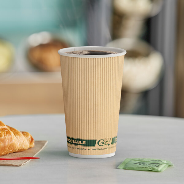 A close-up of a EcoChoice Double Wall Kraft Paper Hot Cup filled with coffee on a table with a croissant.