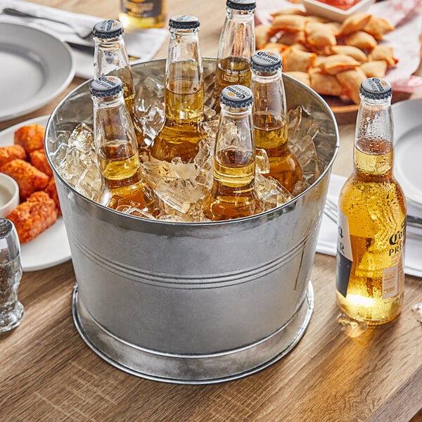 A Choice metal bucket filled with beer bottles on a table on an outdoor patio.