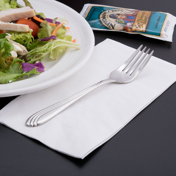 A Libbey stainless steel salad fork on a plate of salad with chicken.