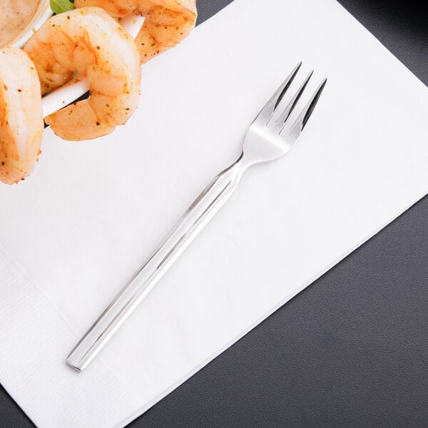 A Libbey stainless steel cocktail fork with shrimp on it on a white napkin.