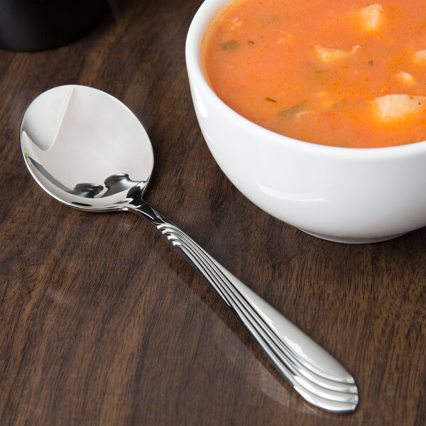 A bowl of soup with a Libbey Neptune bouillon spoon.