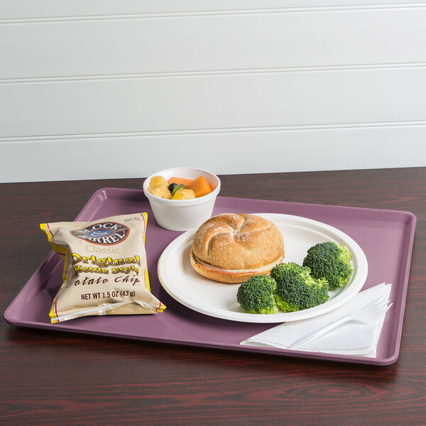 A Cambro grape dietary tray with food on it, including a sandwich, broccoli, and potato chips.