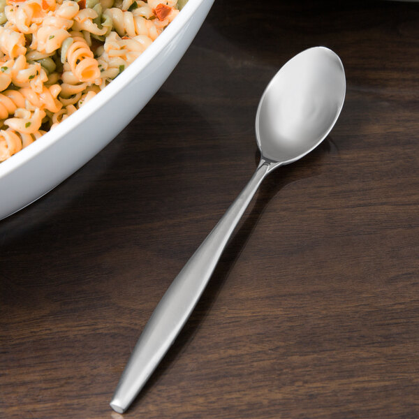 A silver Libbey Slenda serving spoon in a bowl of pasta.