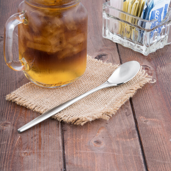 A glass of iced tea with a Libbey stainless steel iced tea spoon in it on a counter.