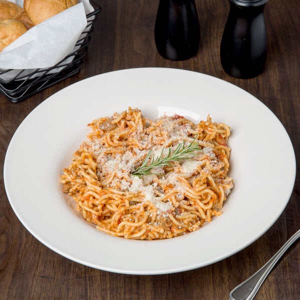 A Libbey ivory porcelain pasta bowl filled with spaghetti and cheese on a table.