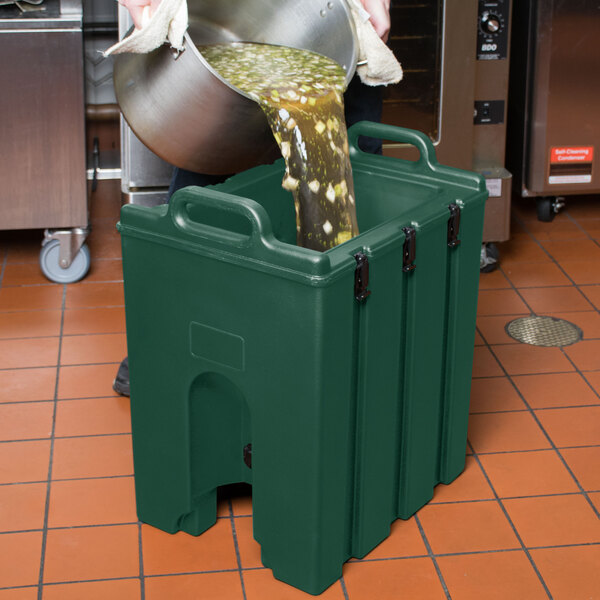 A person pouring liquid into a green Cambro soup carrier.