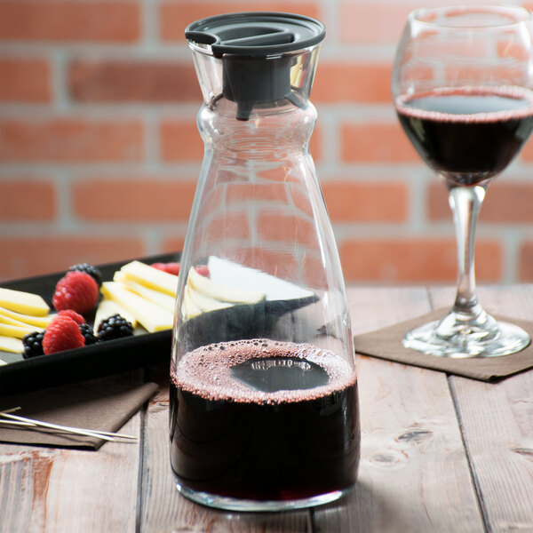 An Arcoroc fluid carafe filled with red wine on a table.
